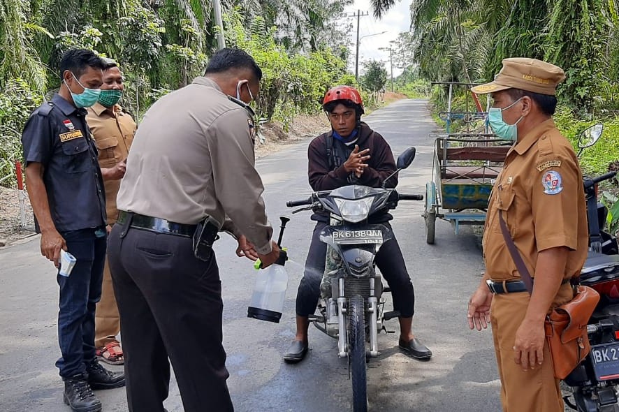 Polsek Tiga Juhar Bersama Perangkat Desa Turun ke Jalan Semprot Disinfektan
